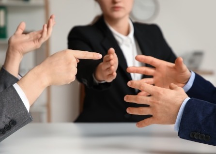 Three people in business attire sit at a table having a heated discussion, with their hands gesturing emphatically—much like clients and a Houston family law attorney navigating complex legal matters.