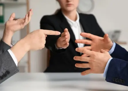 Three people in business attire sit at a table having a heated discussion, with their hands gesturing emphatically—much like clients and a Houston family law attorney navigating complex legal matters.